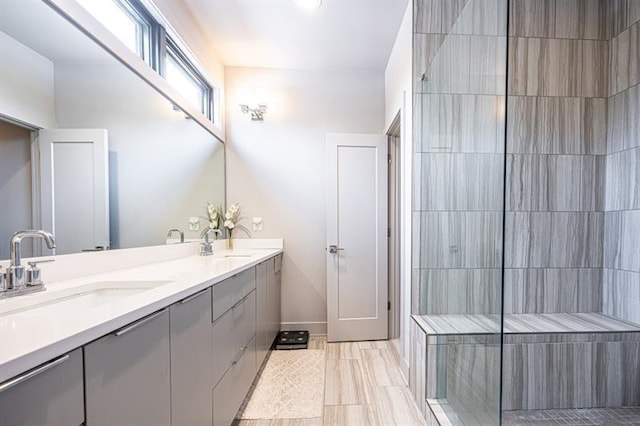 bathroom with a sink, double vanity, and a tile shower