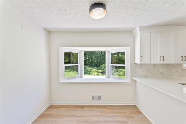 145 Devilla Trce, Fayetteville, GA 30214 - kitchen with white cabinets, tasteful backsplash, light wood-style flooring, light countertops, and baseboards