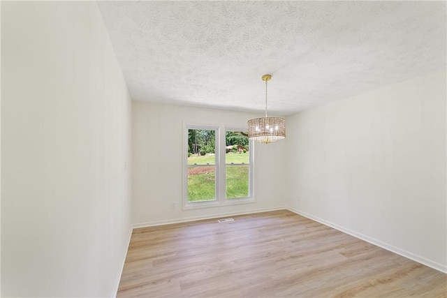 145 Devilla Trce, Fayetteville, GA 30214 - empty room featuring a chandelier, light wood-type flooring, a textured ceiling, and baseboards