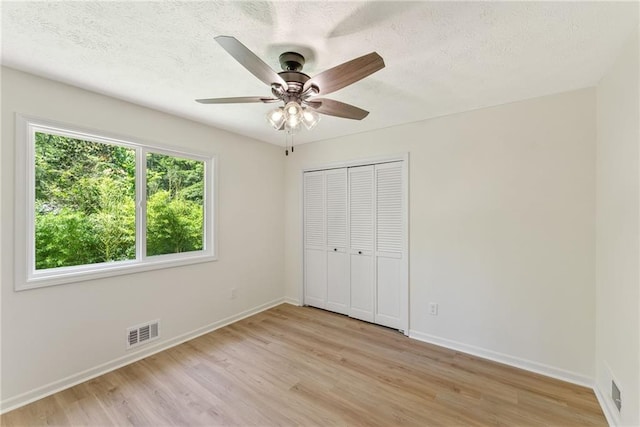 145 Devilla Trce, Fayetteville, GA 30214 - unfurnished bedroom with light wood-style flooring, baseboards, a closet, a textured ceiling, and ceiling fan