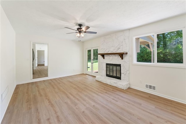 145 Devilla Trce, Fayetteville, GA 30214 - unfurnished living room with light wood-style floors, a stone fireplace, ceiling fan, and baseboards