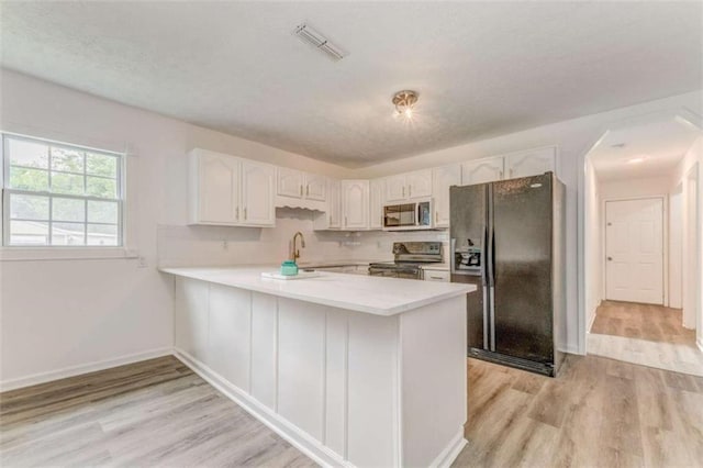 53 Knight Dr, Cedartown, GA 30125 - kitchen with appliances with stainless steel finishes, a peninsula, light wood-style flooring, light countertops, and white cabinets