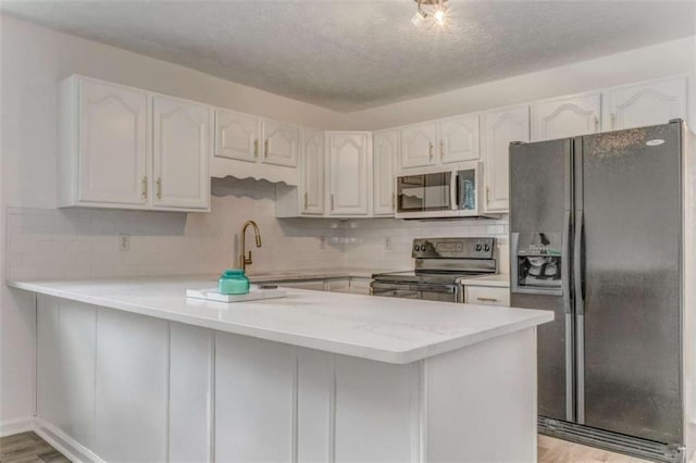 53 Knight Dr, Cedartown, GA 30125 - kitchen with black appliances, a peninsula, white cabinets, decorative backsplash, and light wood finished floors