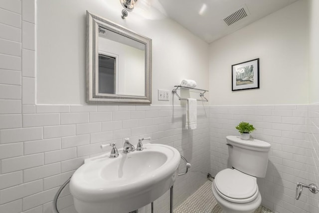 1038 Saint Charles Ave, Atlanta, GA 30306 - half bathroom featuring tile walls, a wainscoted wall, toilet, a sink, and tile patterned flooring