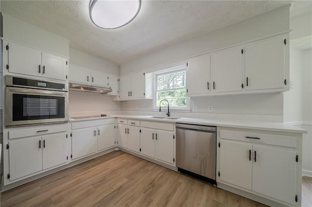 4732 Manly Ct, Stone Mountain, GA 30088 - kitchen with appliances with stainless steel finishes, light wood-style flooring, white cabinets, a sink, and light countertops