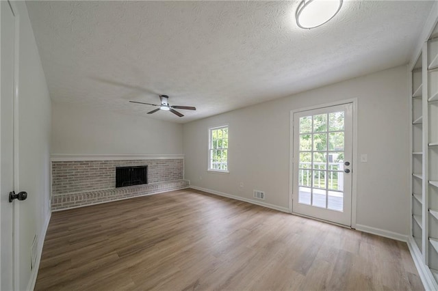 4732 Manly Ct, Stone Mountain, GA 30088 - unfurnished living room with a textured ceiling, a ceiling fan, wood finished floors, baseboards, and a brick fireplace