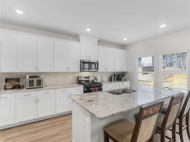 kitchen with a center island with sink, white cabinets, sink, and stainless steel appliances