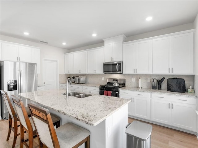 kitchen with a center island with sink, white cabinetry, sink, and appliances with stainless steel finishes