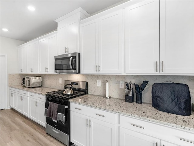 kitchen featuring white cabinets, light hardwood / wood-style floors, backsplash, and appliances with stainless steel finishes