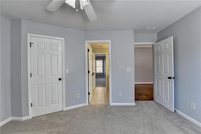 unfurnished bedroom featuring a closet, light colored carpet, and ceiling fan