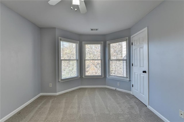 carpeted spare room featuring ceiling fan and a healthy amount of sunlight