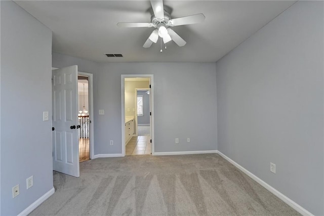 unfurnished bedroom with ensuite bath, light carpet, and ceiling fan