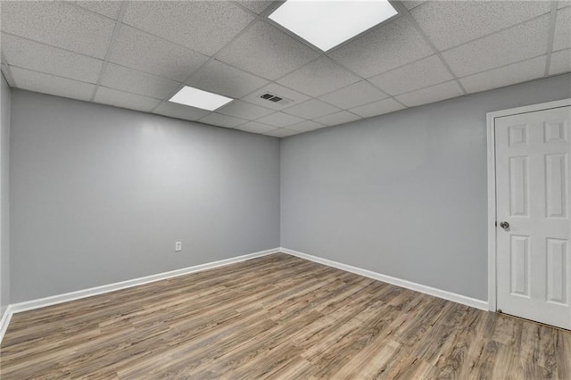 empty room with a drop ceiling and wood-type flooring