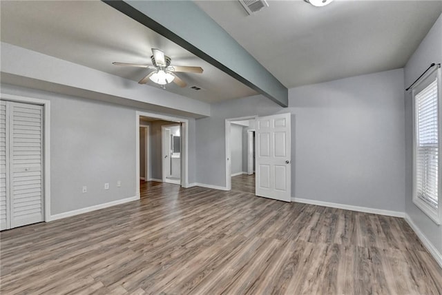 unfurnished bedroom featuring hardwood / wood-style floors, ceiling fan, and beam ceiling