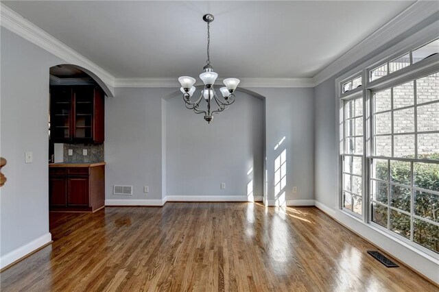 kitchen featuring a center island, crown molding, decorative light fixtures, black appliances, and light wood-type flooring