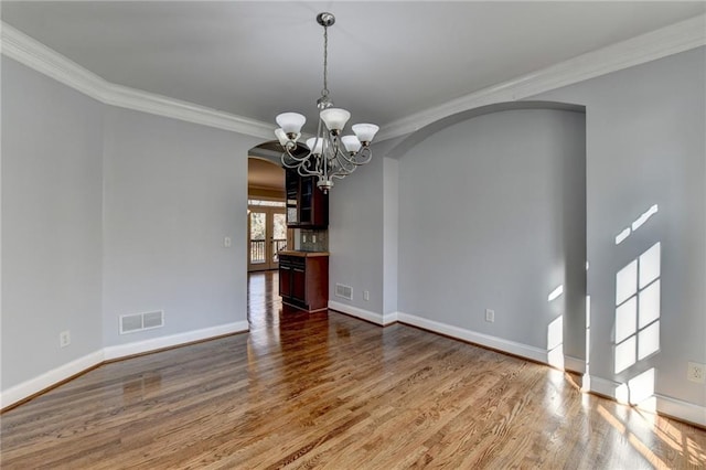 kitchen with dark stone counters, crown molding, black appliances, light hardwood / wood-style flooring, and hanging light fixtures