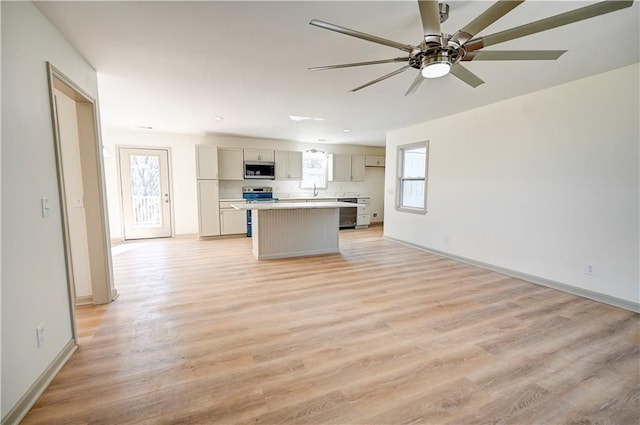 kitchen featuring ceiling fan, stainless steel appliances, a kitchen island, and light wood-type flooring