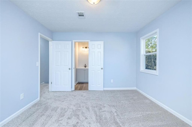 unfurnished bedroom featuring a textured ceiling and light colored carpet