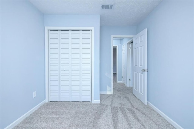 unfurnished bedroom with light carpet, a closet, and a textured ceiling