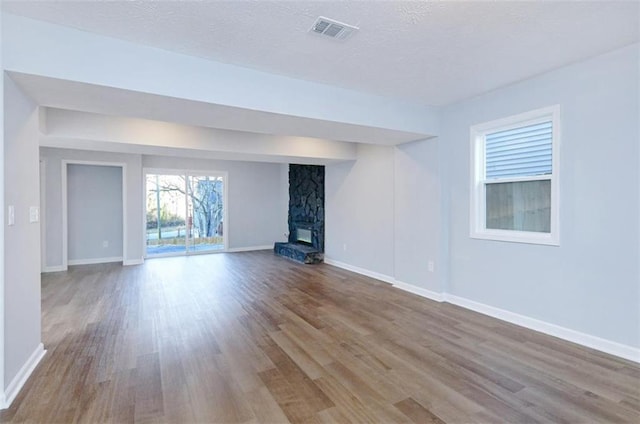 unfurnished living room with a fireplace, a textured ceiling, and light wood-type flooring