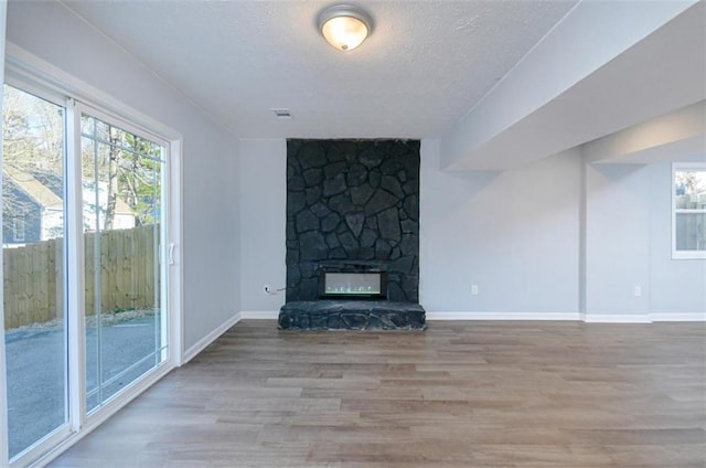 unfurnished living room with a fireplace, wood-type flooring, and a textured ceiling