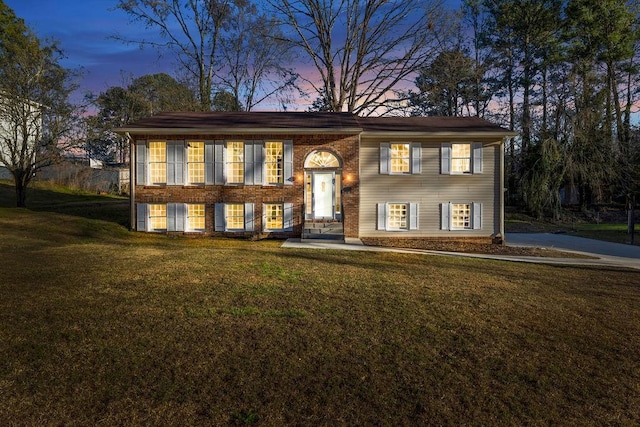 split foyer home featuring a yard and brick siding