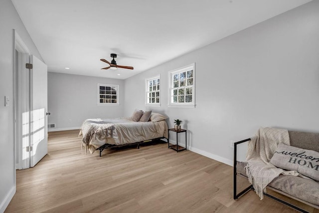 bedroom with ceiling fan, light wood-type flooring, visible vents, and baseboards