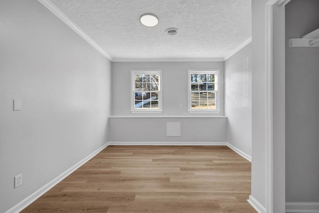 spare room with light wood-style floors, visible vents, crown molding, and baseboards