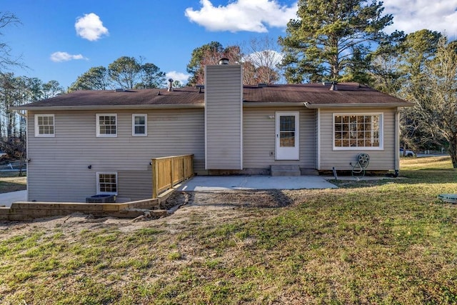 back of house featuring a patio, a lawn, and a chimney