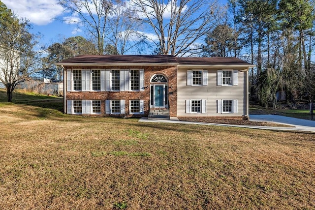 raised ranch with brick siding and a front yard