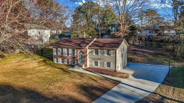 raised ranch featuring a front yard, concrete driveway, and brick siding