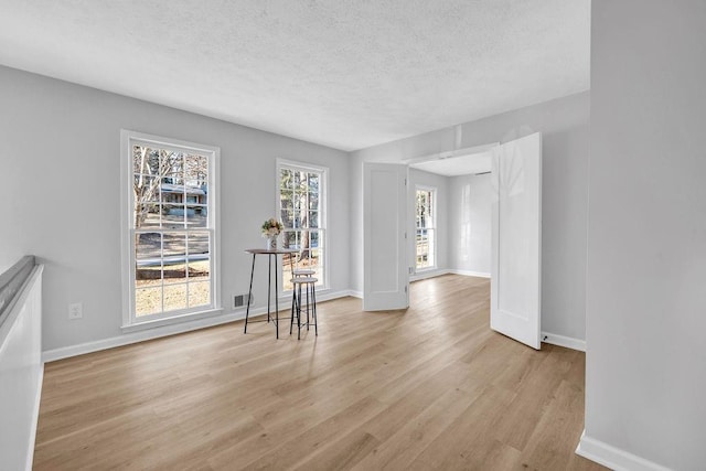 empty room with a textured ceiling, baseboards, and wood finished floors