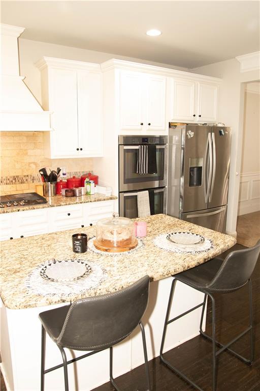 305 Anise Ct, Mcdonough, GA 30252 - kitchen with freestanding refrigerator, a breakfast bar, a sink, dark wood finished floors, and white cabinets