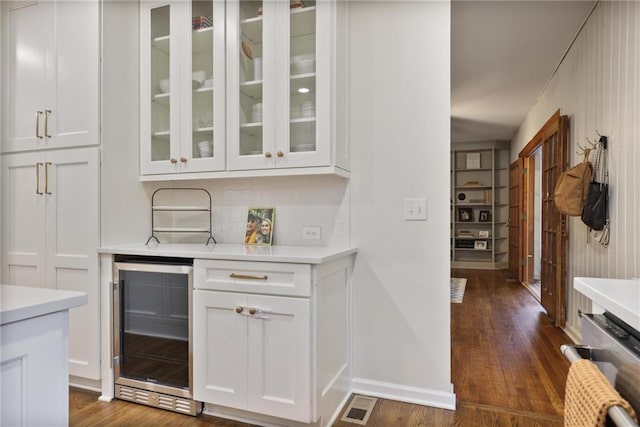 bar with dark hardwood / wood-style flooring, white cabinetry, wine cooler, and backsplash