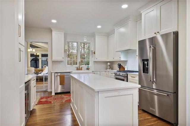 kitchen with white cabinets, premium appliances, a kitchen island, and backsplash