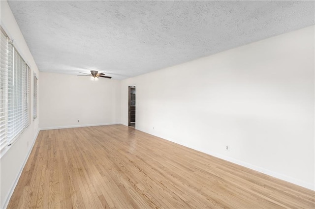 spare room with light wood finished floors, baseboards, a ceiling fan, and a textured ceiling