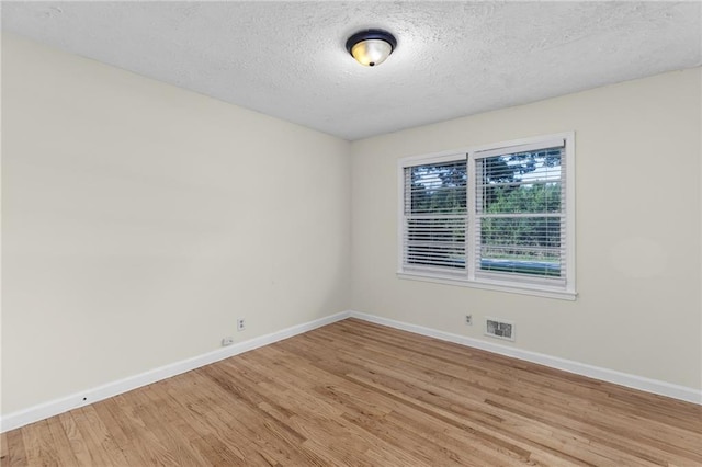 unfurnished room featuring visible vents, light wood-style flooring, baseboards, and a textured ceiling