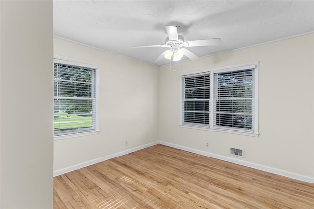 empty room featuring light wood finished floors, baseboards, visible vents, and a ceiling fan