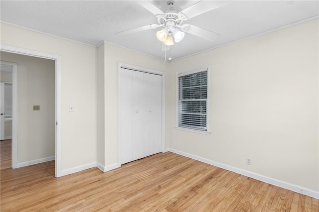 unfurnished bedroom with light wood-style flooring, a ceiling fan, baseboards, ornamental molding, and a closet