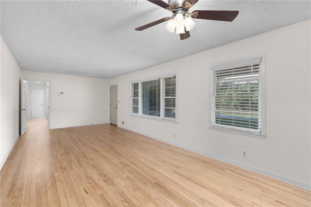 spare room with baseboards, ceiling fan, light wood-style flooring, and a textured ceiling