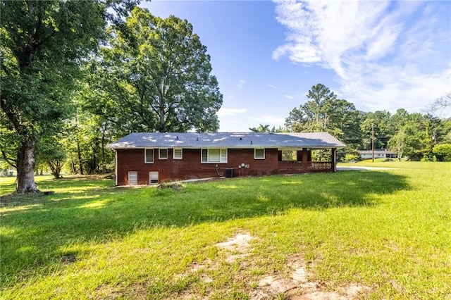 back of property with brick siding, a yard, and central AC unit