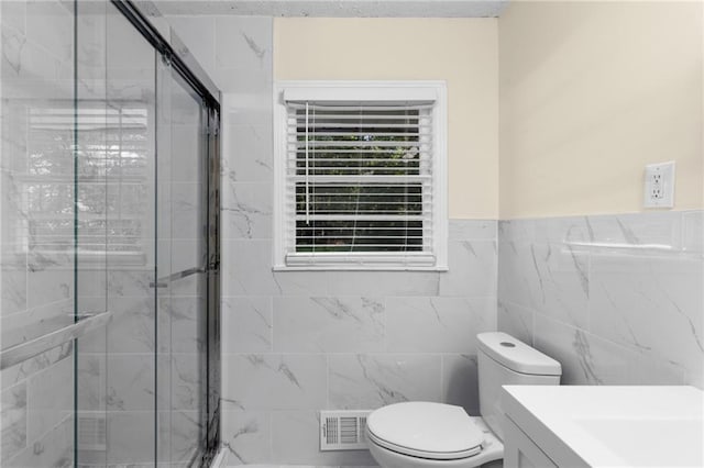 bathroom with tile walls, a marble finish shower, visible vents, toilet, and vanity