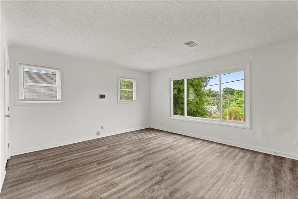 spare room featuring wood-type flooring and a textured ceiling