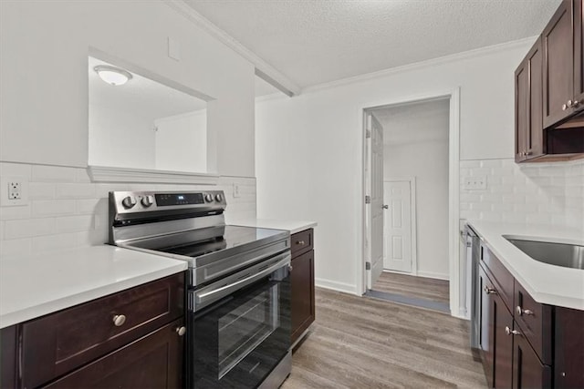 kitchen featuring light wood-type flooring, ornamental molding, a textured ceiling, appliances with stainless steel finishes, and dark brown cabinets