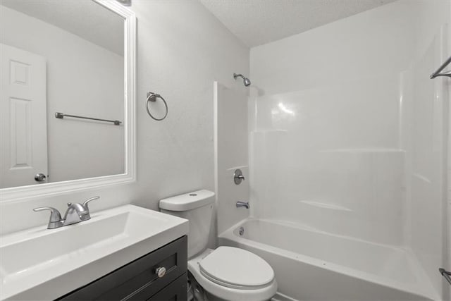 full bathroom featuring vanity, a textured ceiling, toilet, and tub / shower combination