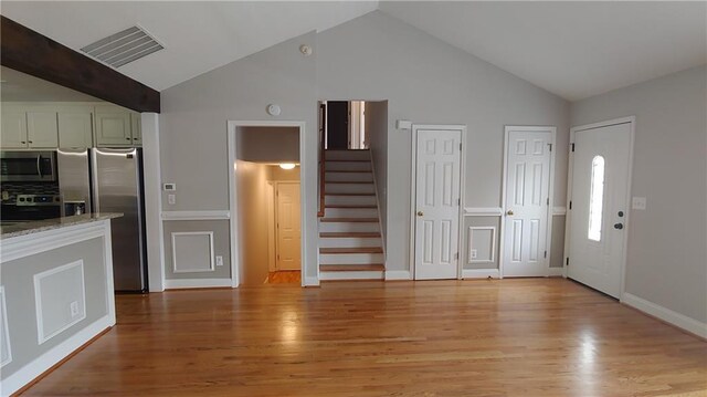2477 Briar Valley Way, Dacula, GA 30019 - unfurnished living room featuring visible vents, light wood finished floors, high vaulted ceiling, and stairway
