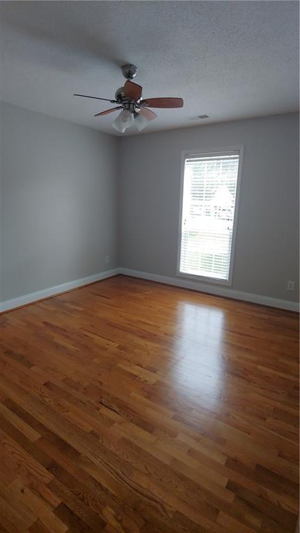 2477 Briar Valley Way, Dacula, GA 30019 - empty room featuring baseboards, a ceiling fan, a textured ceiling, and wood finished floors
