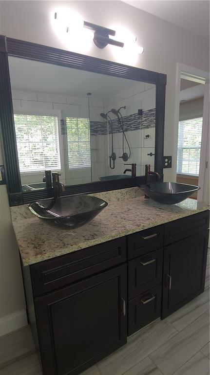 2477 Briar Valley Way, Dacula, GA 30019 - full bath with double vanity, baseboards, a tile shower, and a sink