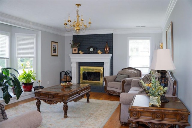 living room with a brick fireplace, light wood-type flooring, a chandelier, and crown molding