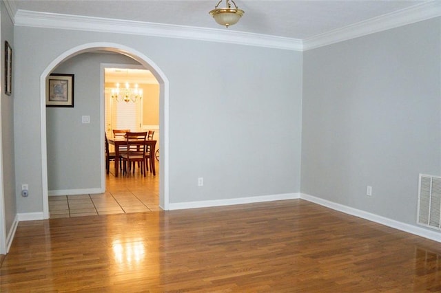 spare room featuring hardwood / wood-style floors, a notable chandelier, and crown molding